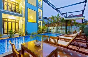 A poolside area with a dining table, lounge chairs, and a pool. - Magnolia Garden Villa (Da Nang)
