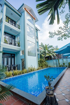 A modern building with a swimming pool, balconies, and tropical plants. - Magnolia Garden Villa (Da Nang)
