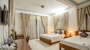 A hotel room with two beds, a TV, a desk with tea sets, and curtains. - Magnolia Garden Villa (Da Nang)