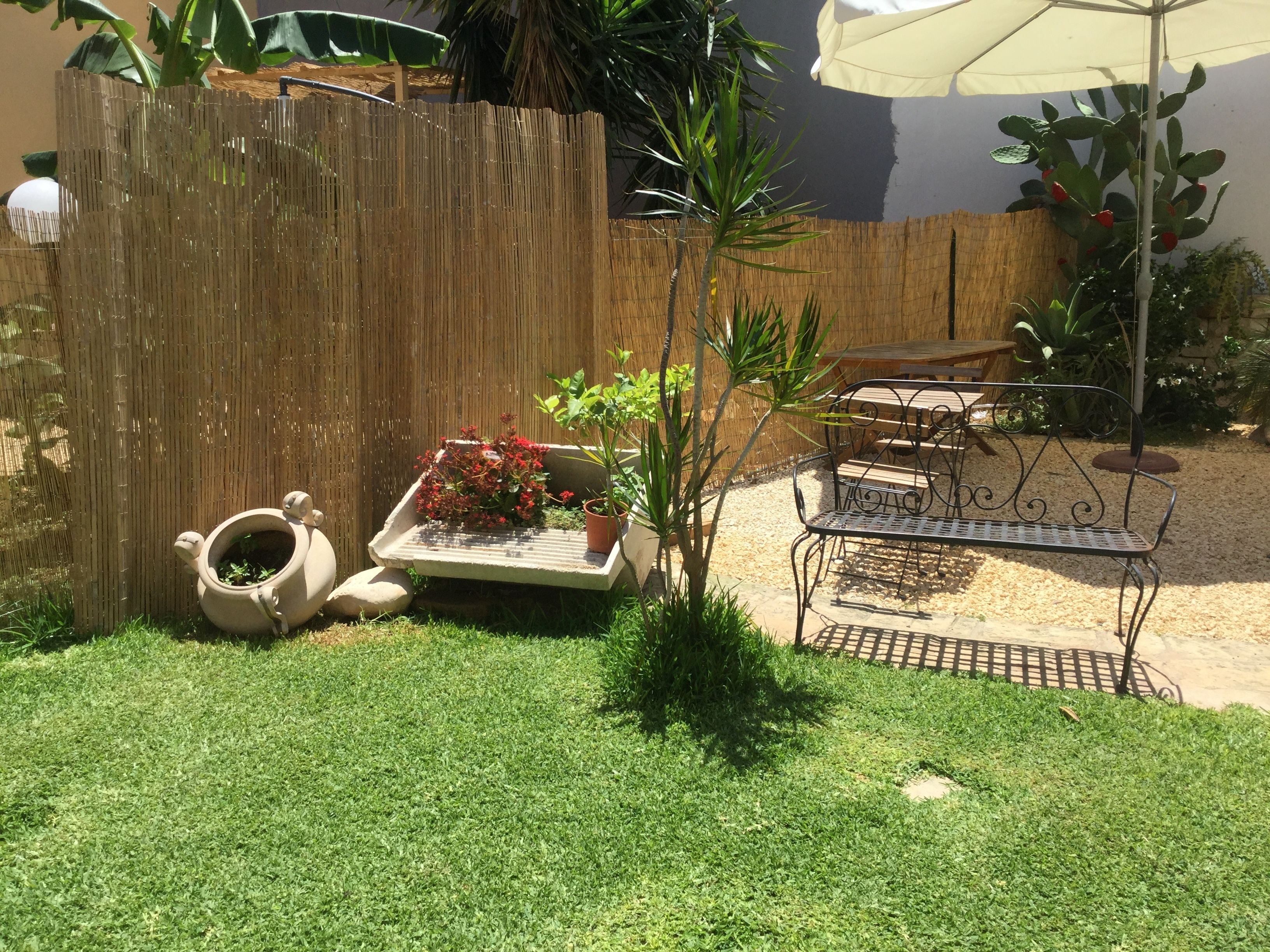 Un giardino con una recinzione di legno, un tavolino con sedie e una pianta in vaso.