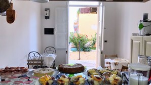 Eine Küche mit Esstisch, gedeckt für eine Mahlzeit, mit verschiedenen Gerichten und Blick ins Freie.