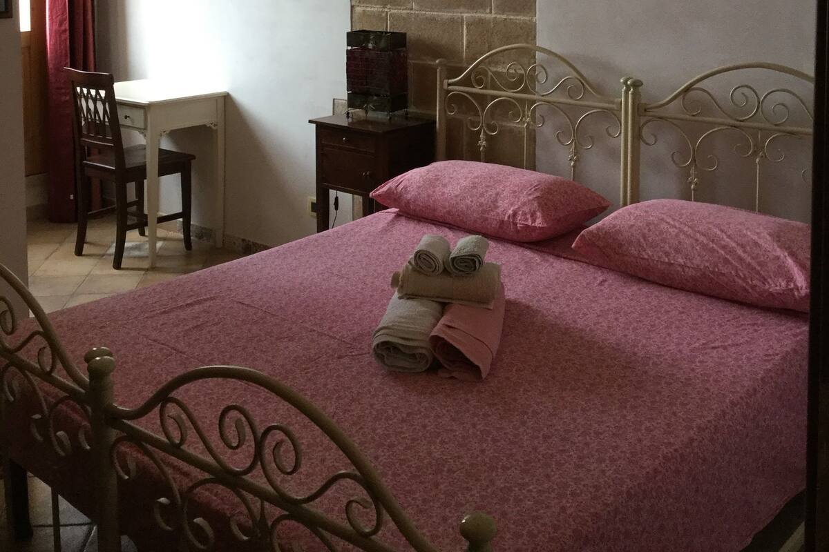 A bedroom with a bed, a desk, and a chair.