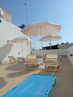 Terraço no telhado com espreguiçadeiras, guarda-sóis e mesa de bilhar.