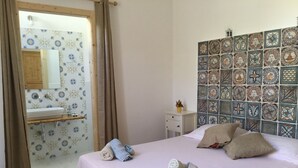 Ein Hotelzimmer mit einem Bett, einem Badezimmer mit Spiegel und einer gefliesten Wand.