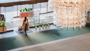 Un vestíbulo moderno con pared de vidrio, plantas en macetas y una lámpara colgante original.