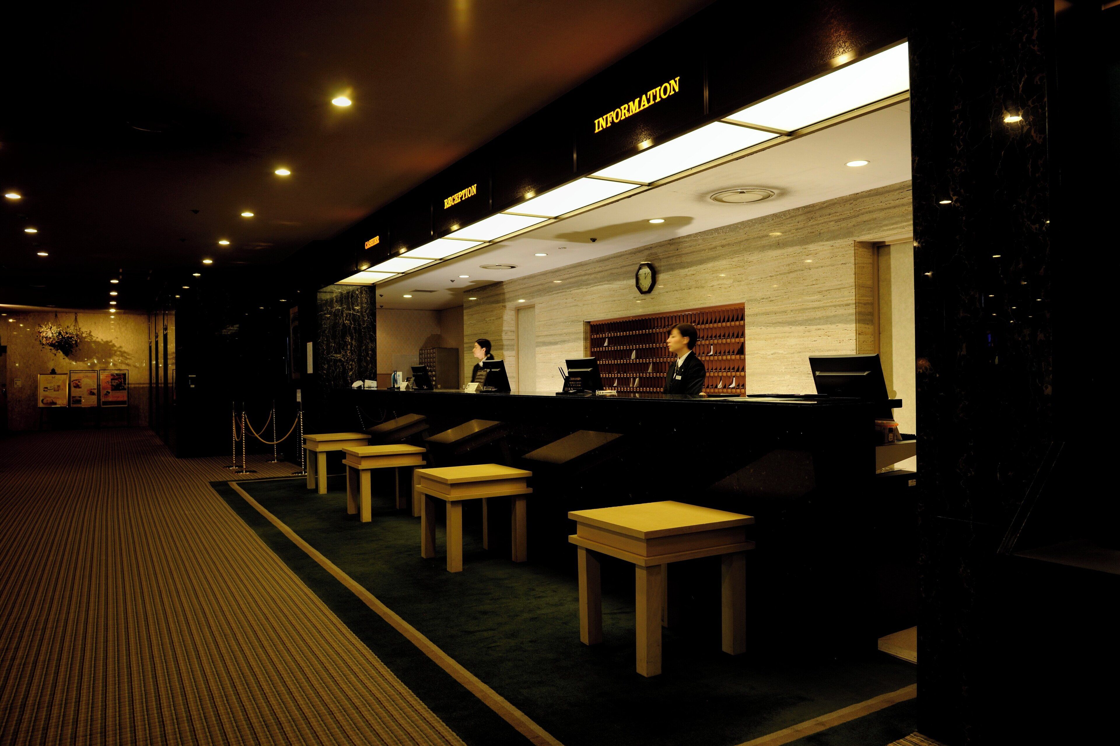 A reception area with a reception desk, a clock, and a seating area with tables and chairs.
