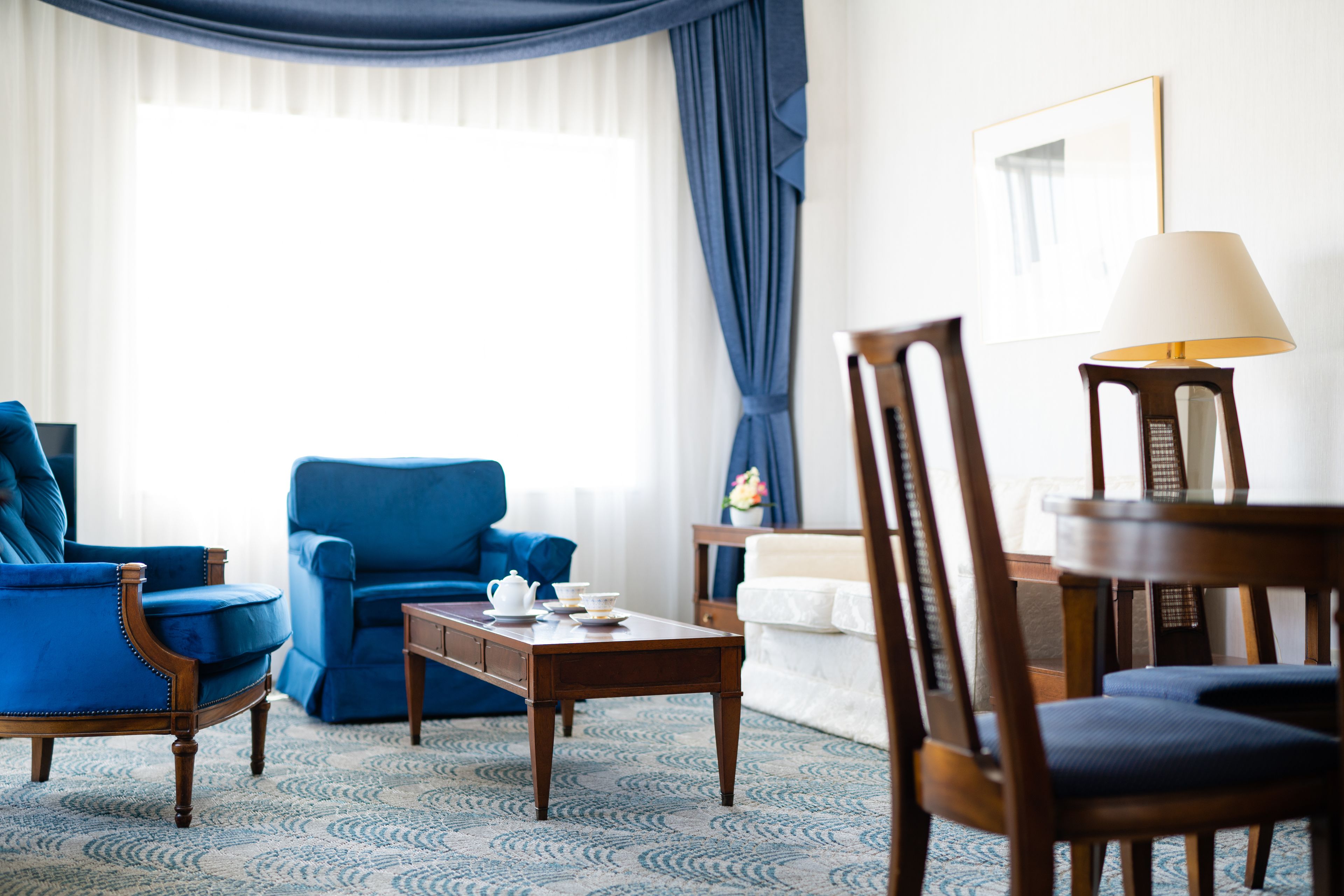 A room with a blue armchair, a wooden coffee table, and a lamp.