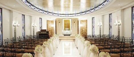 A church interior with pews arranged in rows, a central aisle, and floral decorations.