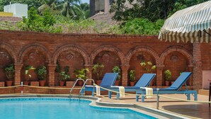A swimming pool with blue lounge chairs and potted plants. - Nanutel Margao (Margao)