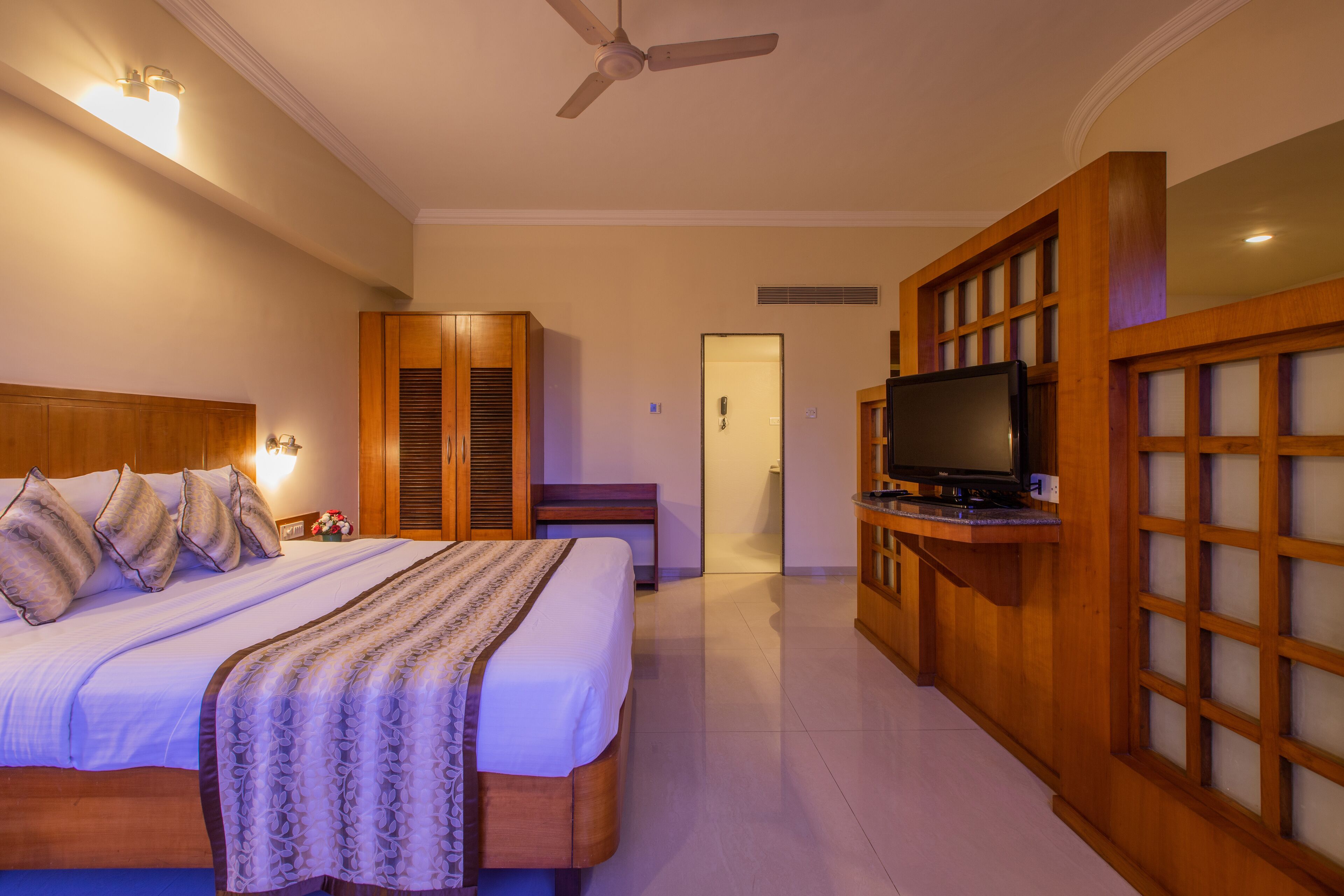 Una habitación de hotel con cama, televisión, armario y puerta que da a otra habitación.