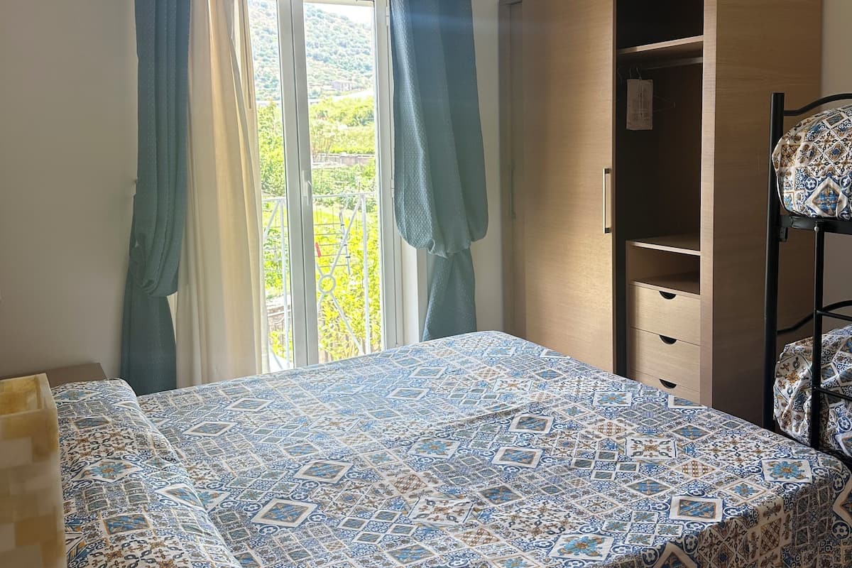 A bedroom with a bed, a wardrobe, and a window with curtains.