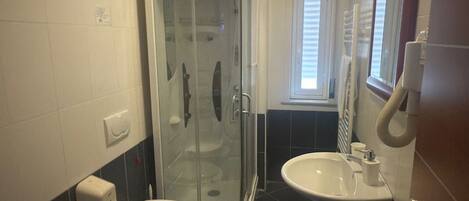 A bathroom with a glass-enclosed shower, two sinks, and a toilet.