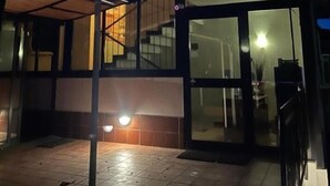 Entrada de hotel com fachada de vidro, área externa coberta e escadaria que leva a um andar superior.