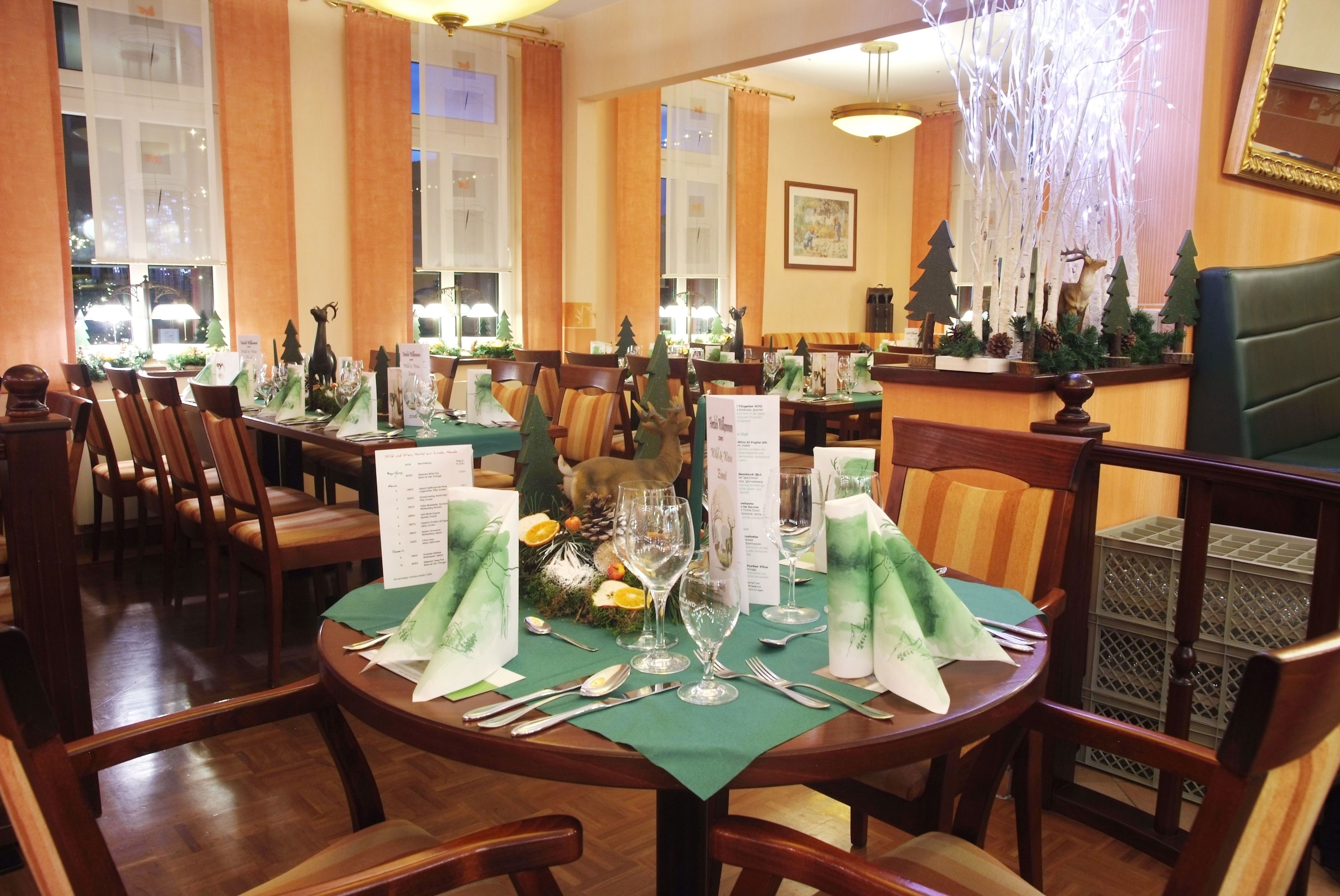 A restaurant with round tables set for dining, featuring green tablecloths and silverware.
