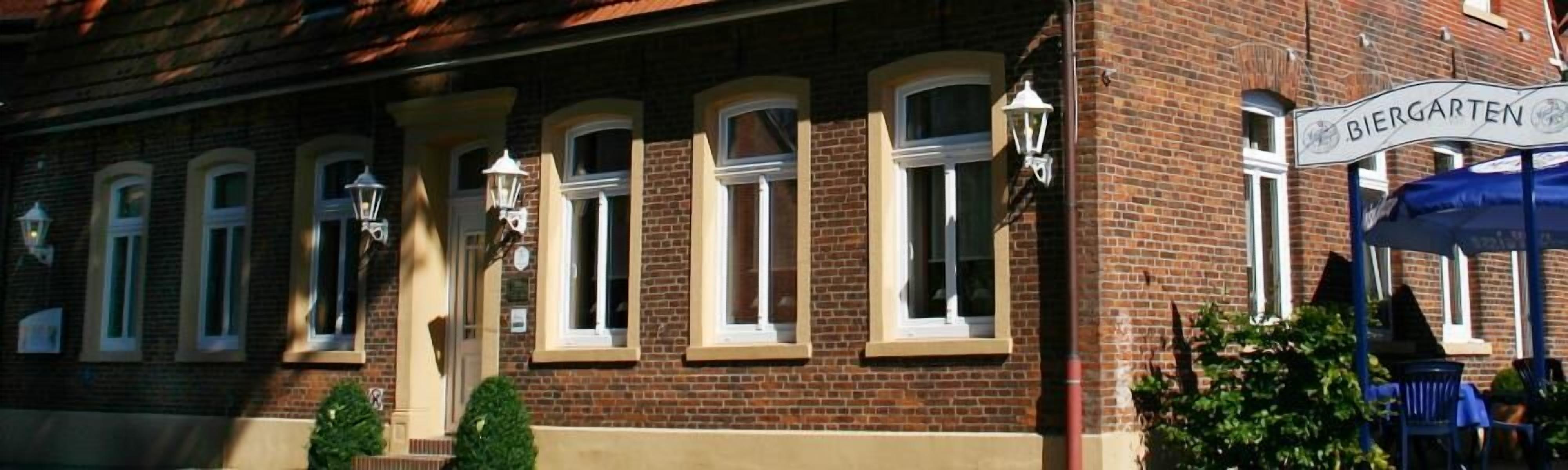 A brick building with multiple windows and a sign that reads "Biergarten".