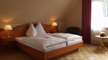 Ein Hotelzimmer mit einem hölzernen Bett, zwei Nachttischlampen, einem Sessel und einem kleinen Tisch mit Blumen.