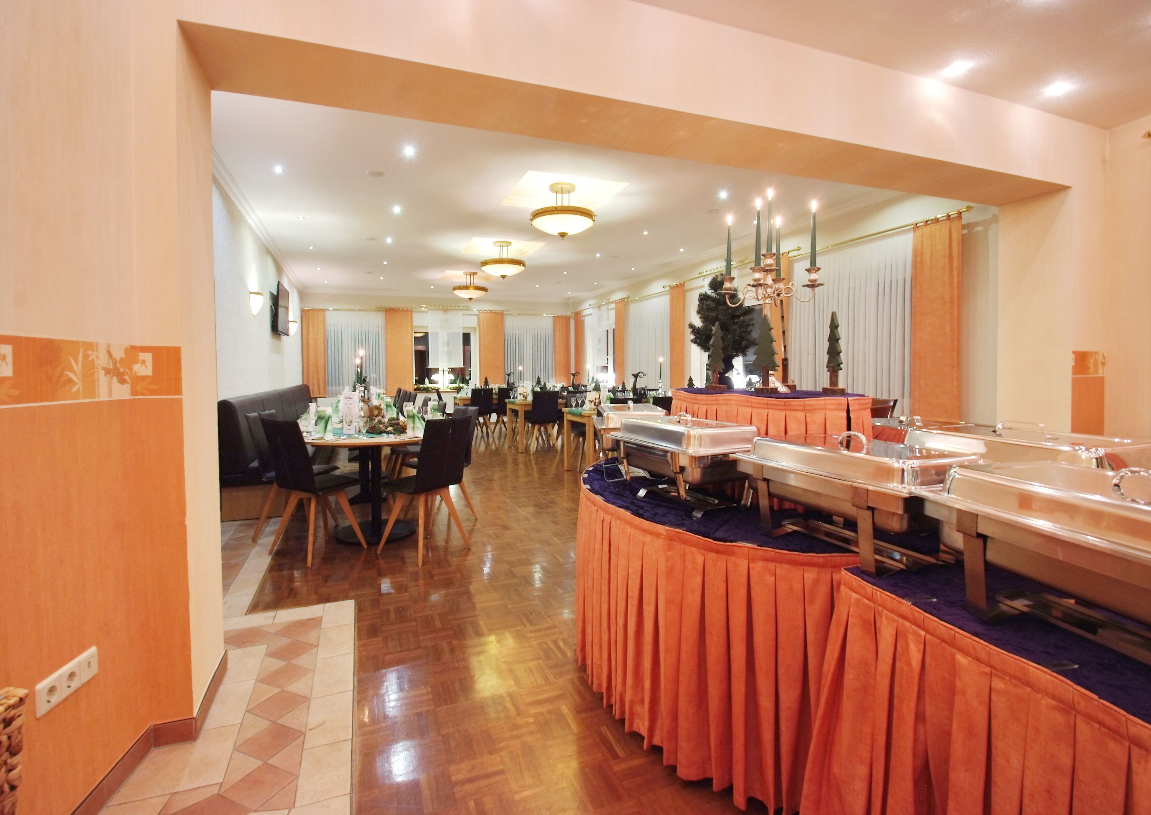 A hotel dining area with multiple tables, chairs, and buffet stations.