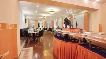 Comedor de hotel con varias mesas, sillas y estaciones de buffet.