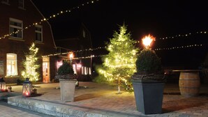 Un edificio de ladrillo con una entrada iluminada, luces exteriores y árboles de Navidad.