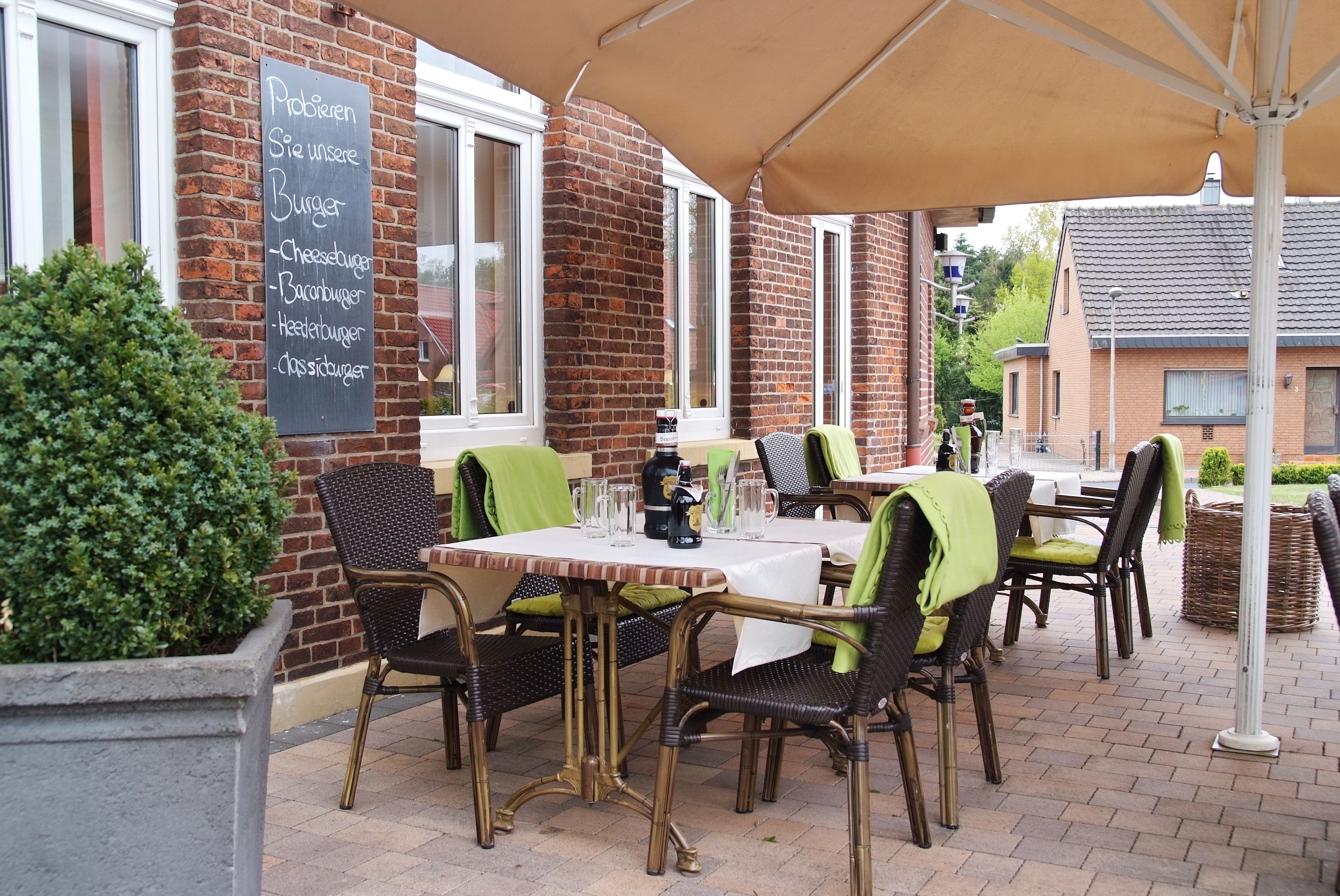 Een terras met bakstenen muren, tafels en stoelen.