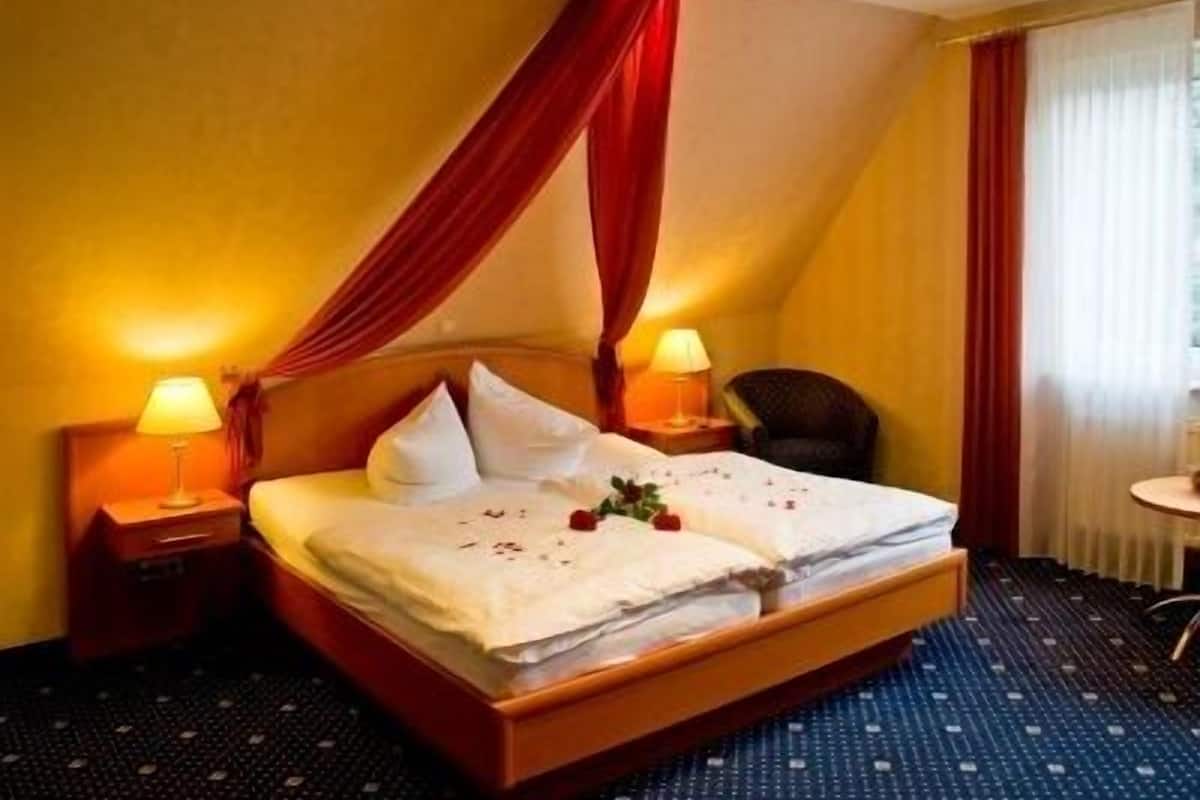 Une chambre d’hôtel avec un lit, deux lampes de chevet, une chaise et une petite table.