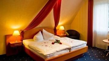 Een hotelkamer met een bed, twee bedlampjes, een stoel en een klein tafeltje.