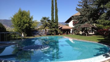 Una piscina al aire libre, sombrillas, sillones reclinables de piscina