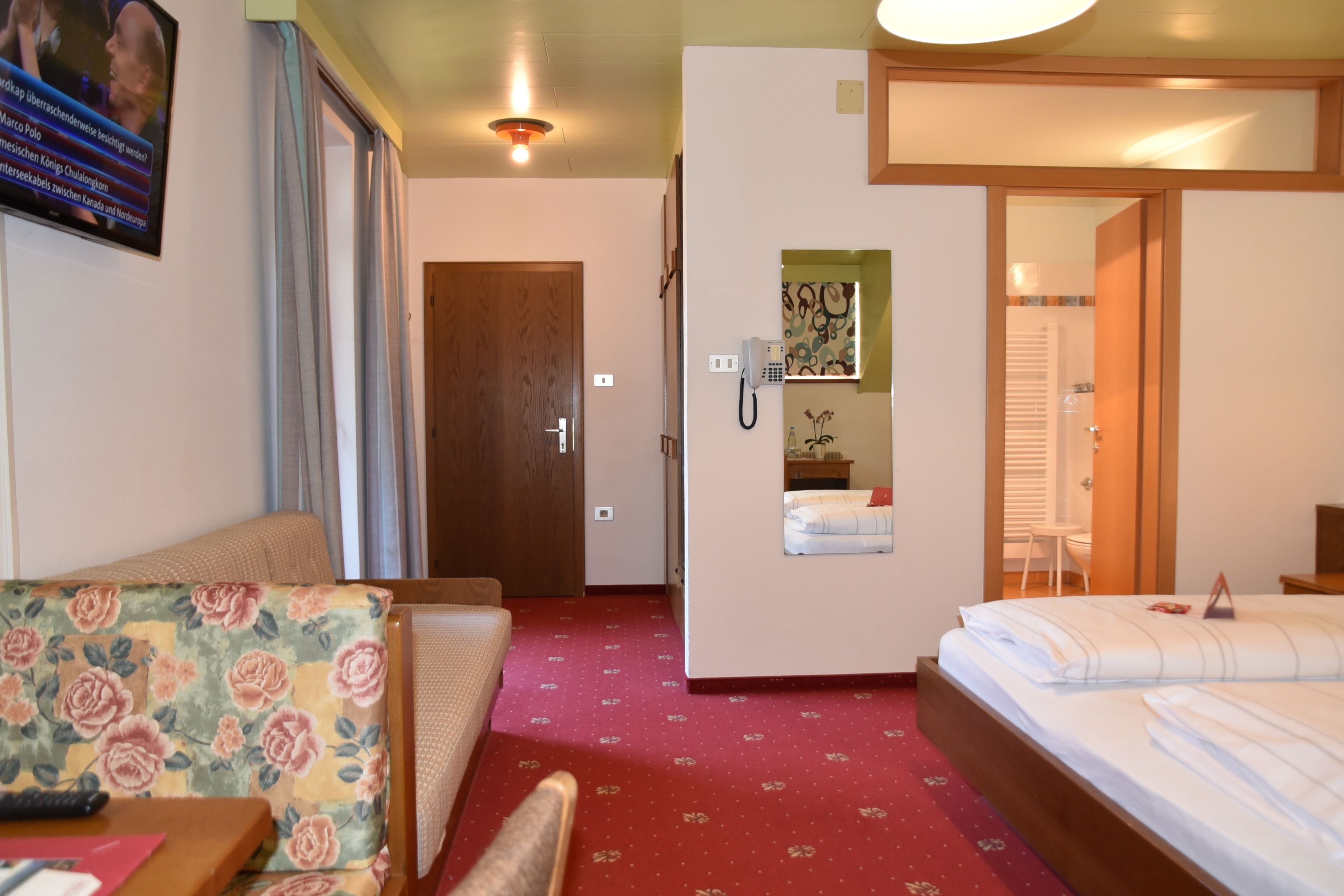 Camera d'albergo con un letto, un divano, un tavolino, un telefono e una finestra con vista.