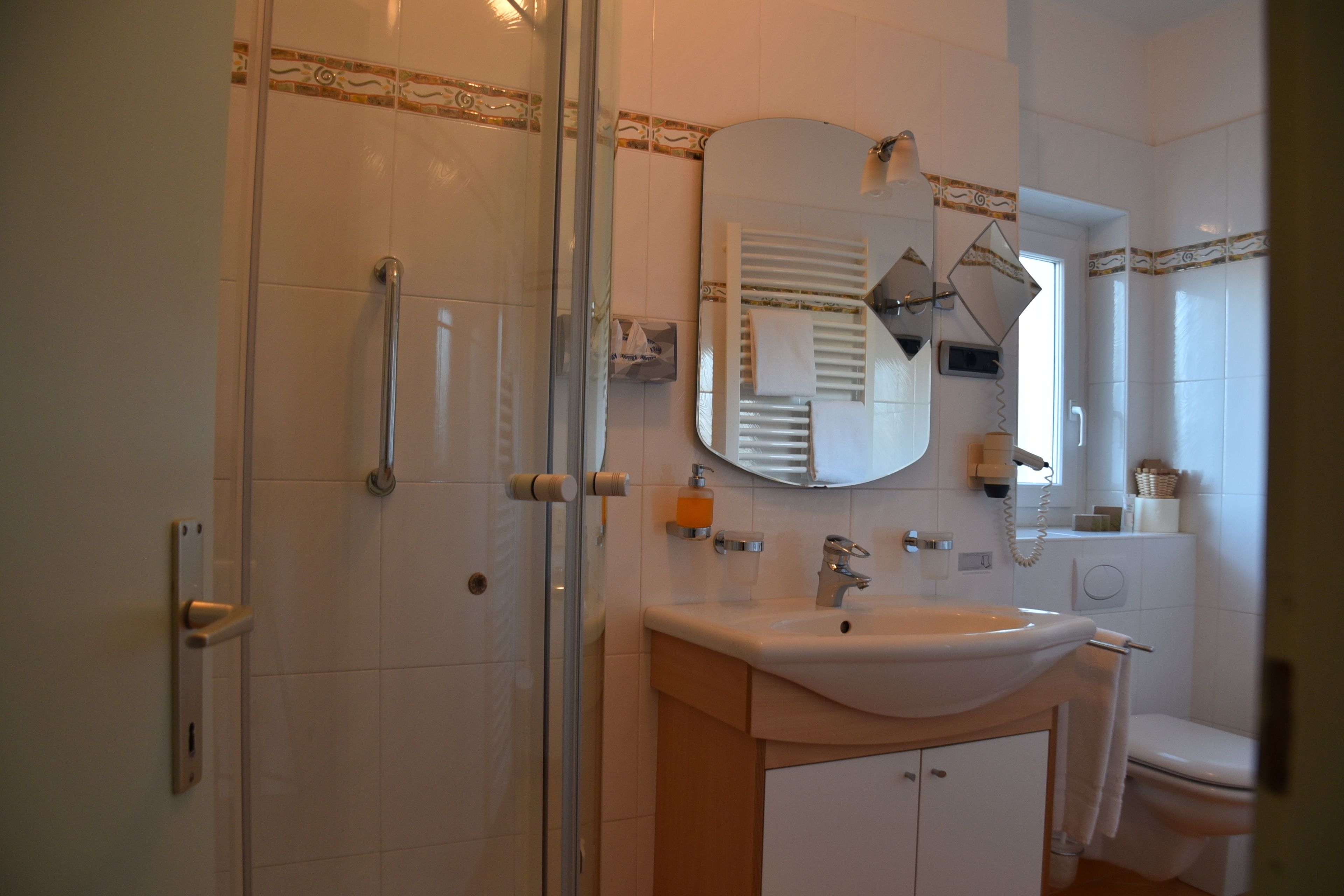 A bathroom with a glass-enclosed shower, a sink with a mirror above it, and a toilet.