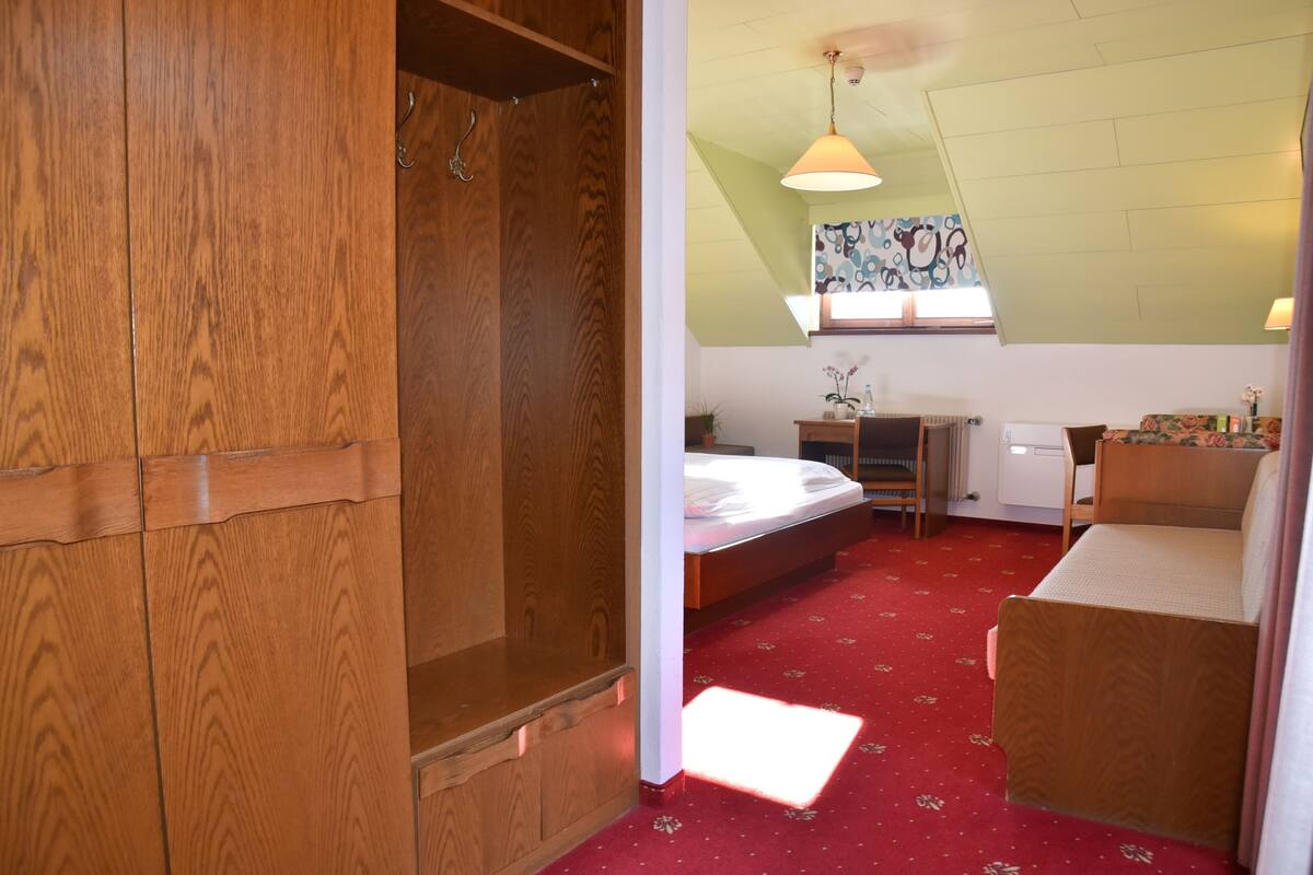 Une chambre à coucher avec un lit, une armoire en bois, un bureau et une chaise.