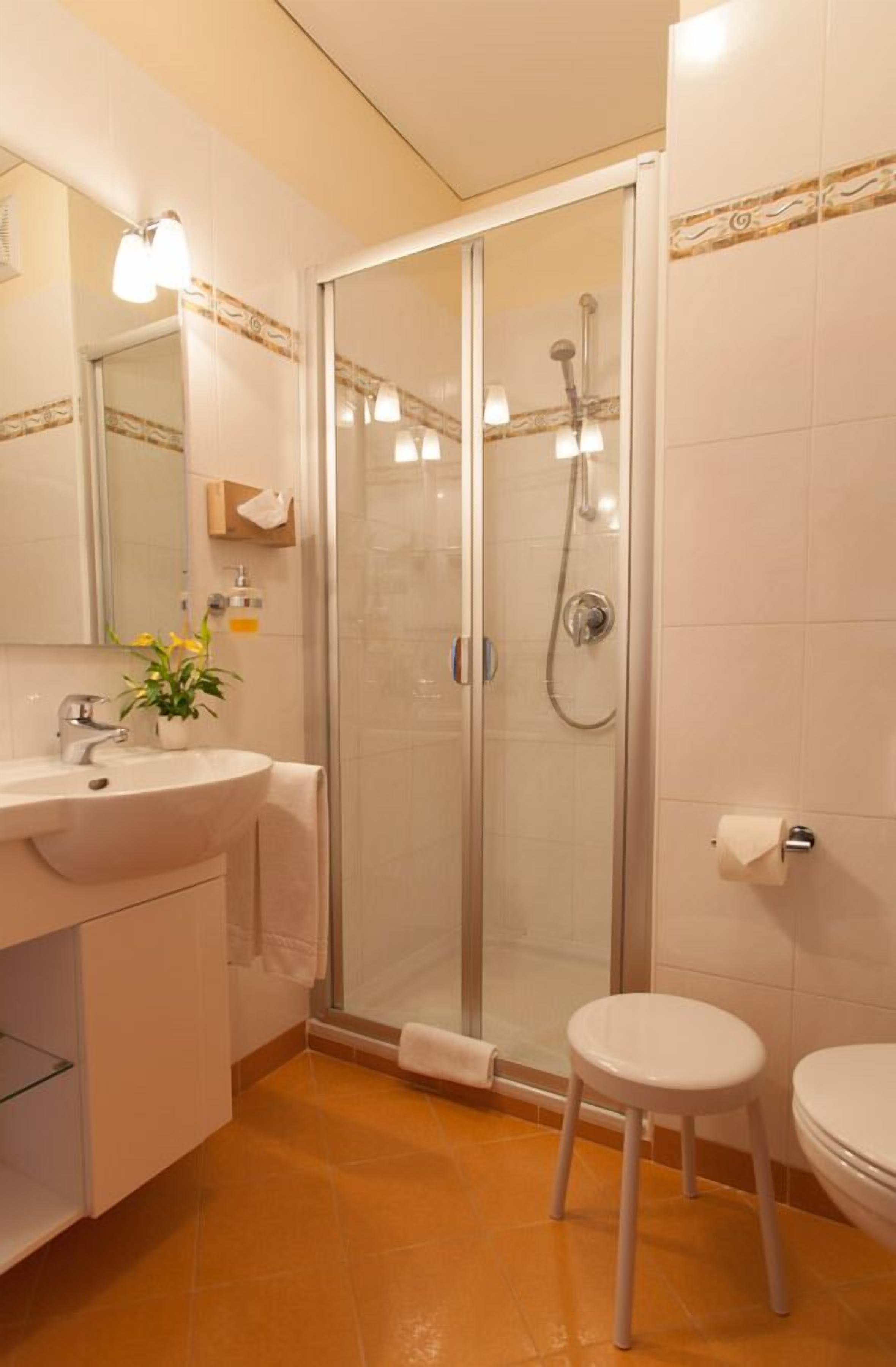 Une salle de bain avec une douche à parois de verre, un lavabo avec un miroir et des toilettes.