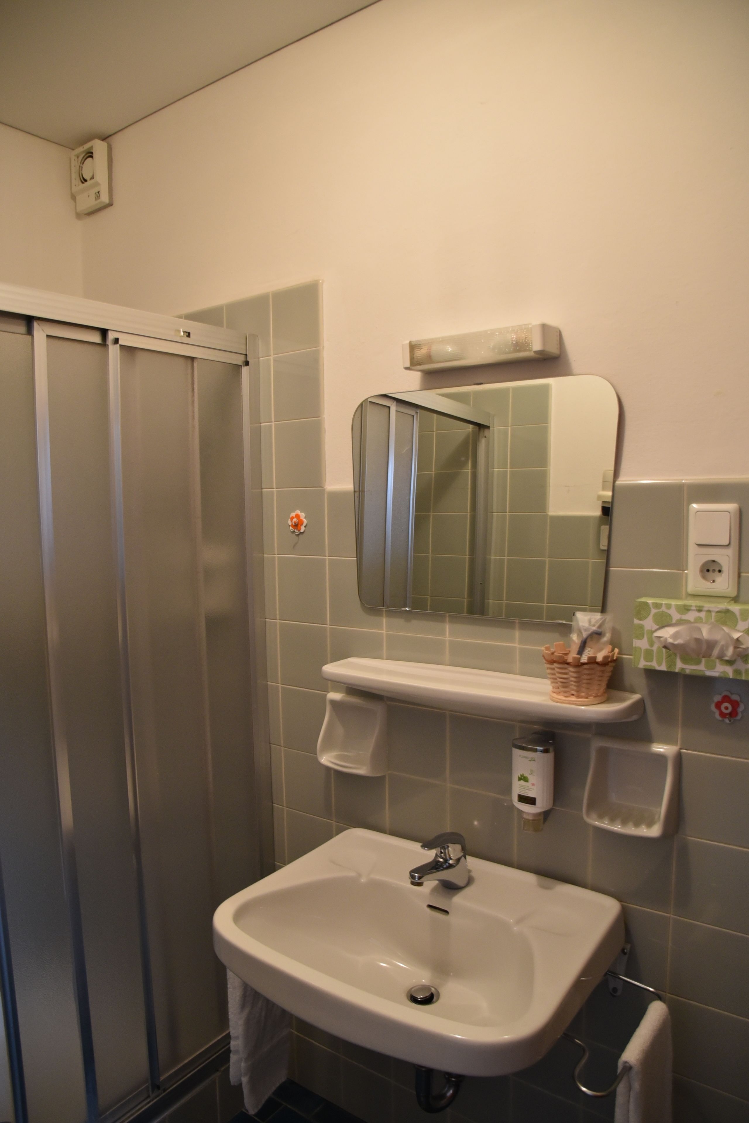 A bathroom with a shower, sink, mirror, and towel rack.