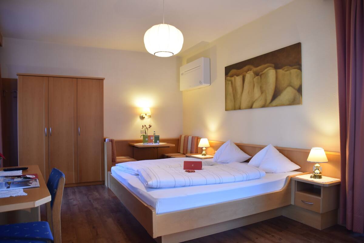 Une chambre d’hôtel comprenant un lit, des tables de chevet, un bureau et une armoire.