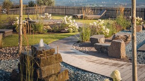 A landscaped garden with a wooden deck, stone features, and a view of distant mountains.