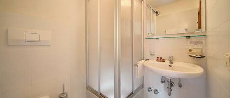 A bathroom with a shower enclosure, a sink, and a toilet.