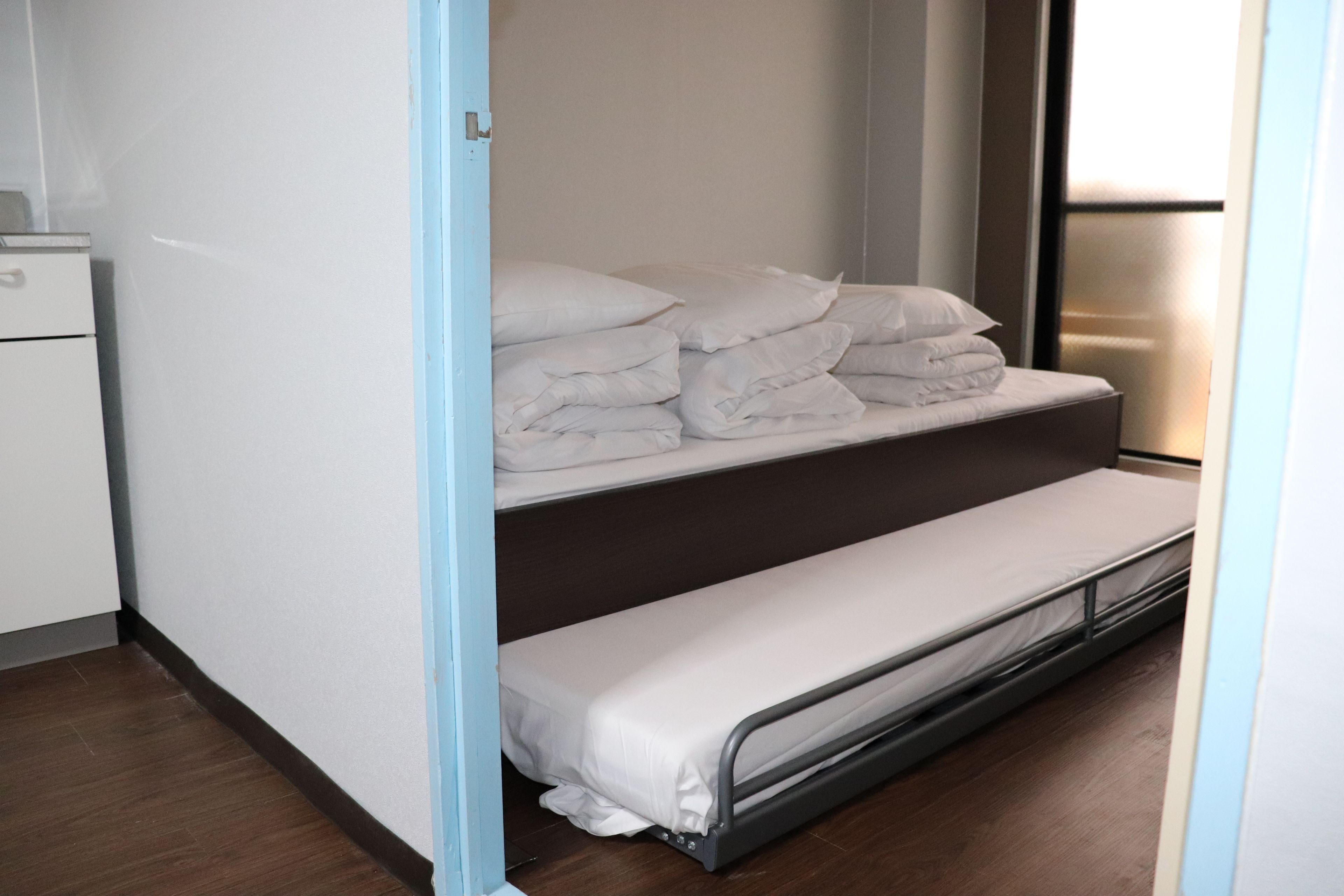 A compact room with a bunk bed, a small desk, and a window.
