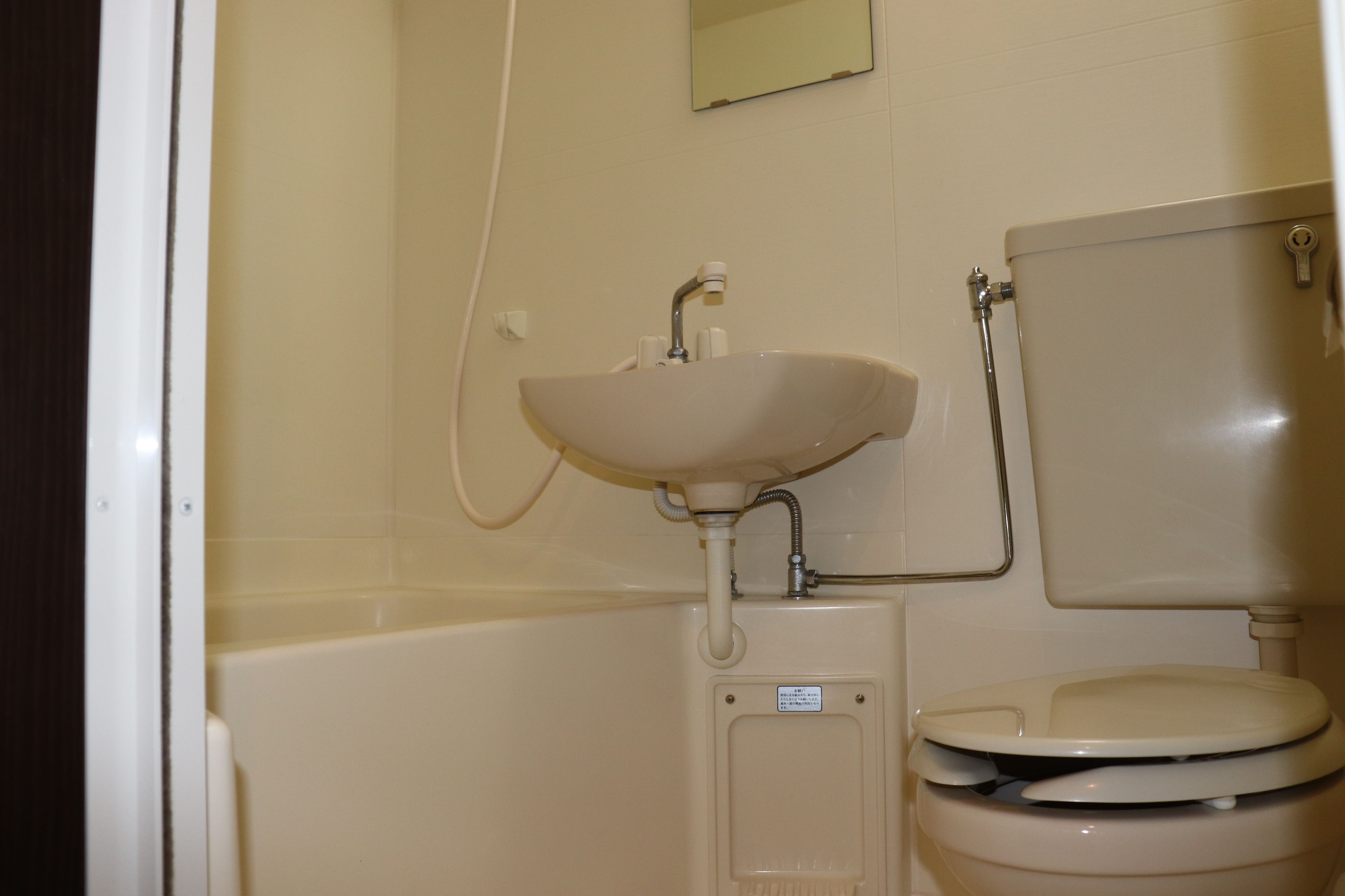 Une salle de bain avec un lavabo, des toilettes et un petit miroir.