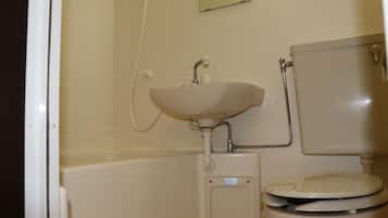 Une salle de bain avec un lavabo, des toilettes et un petit miroir.