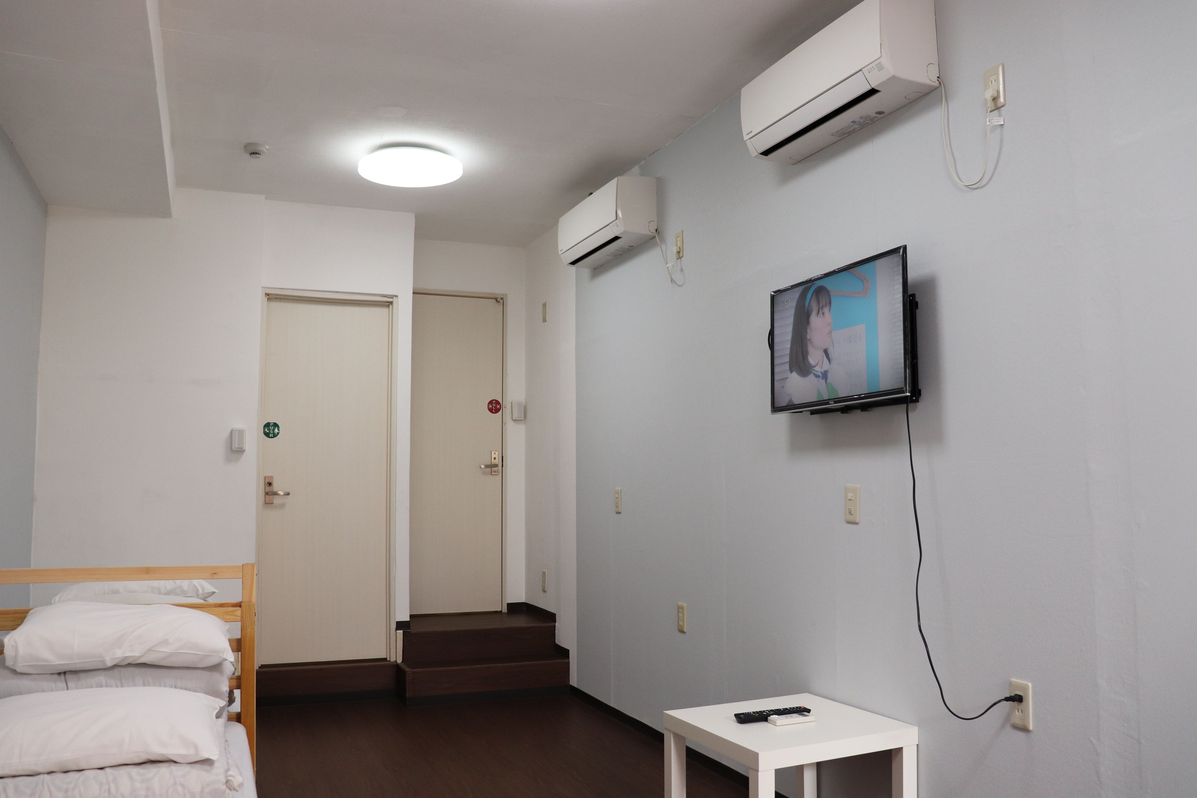 Een hotelkamer met een bed, een aan de muur bevestigde televisie en een klein tafeltje.
