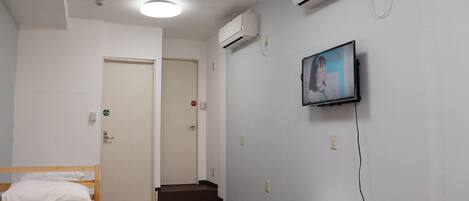 A hotel room with a bed, a TV mounted on the wall, and a small table.