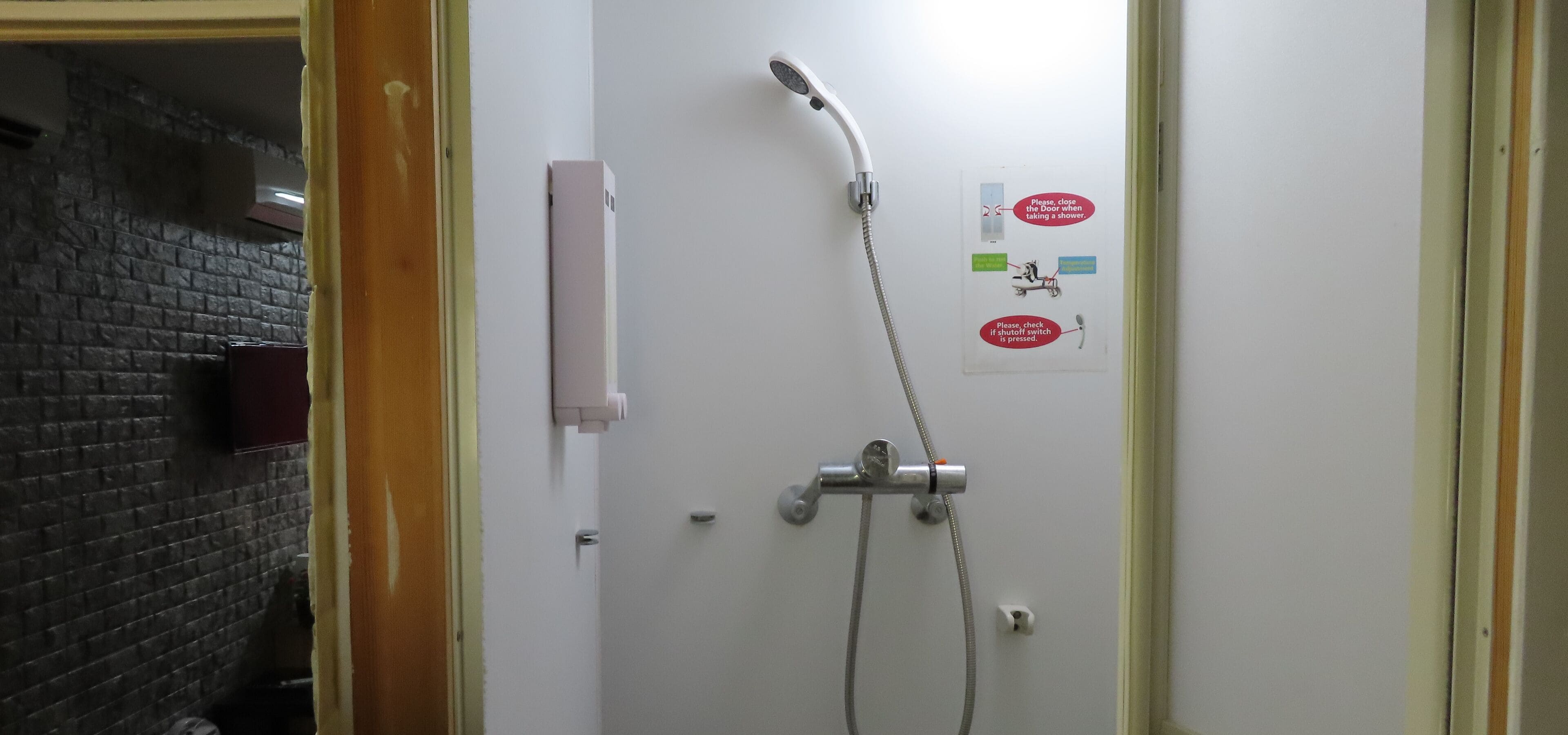 A bathroom with a shower, a towel dispenser, and a sign with instructions.