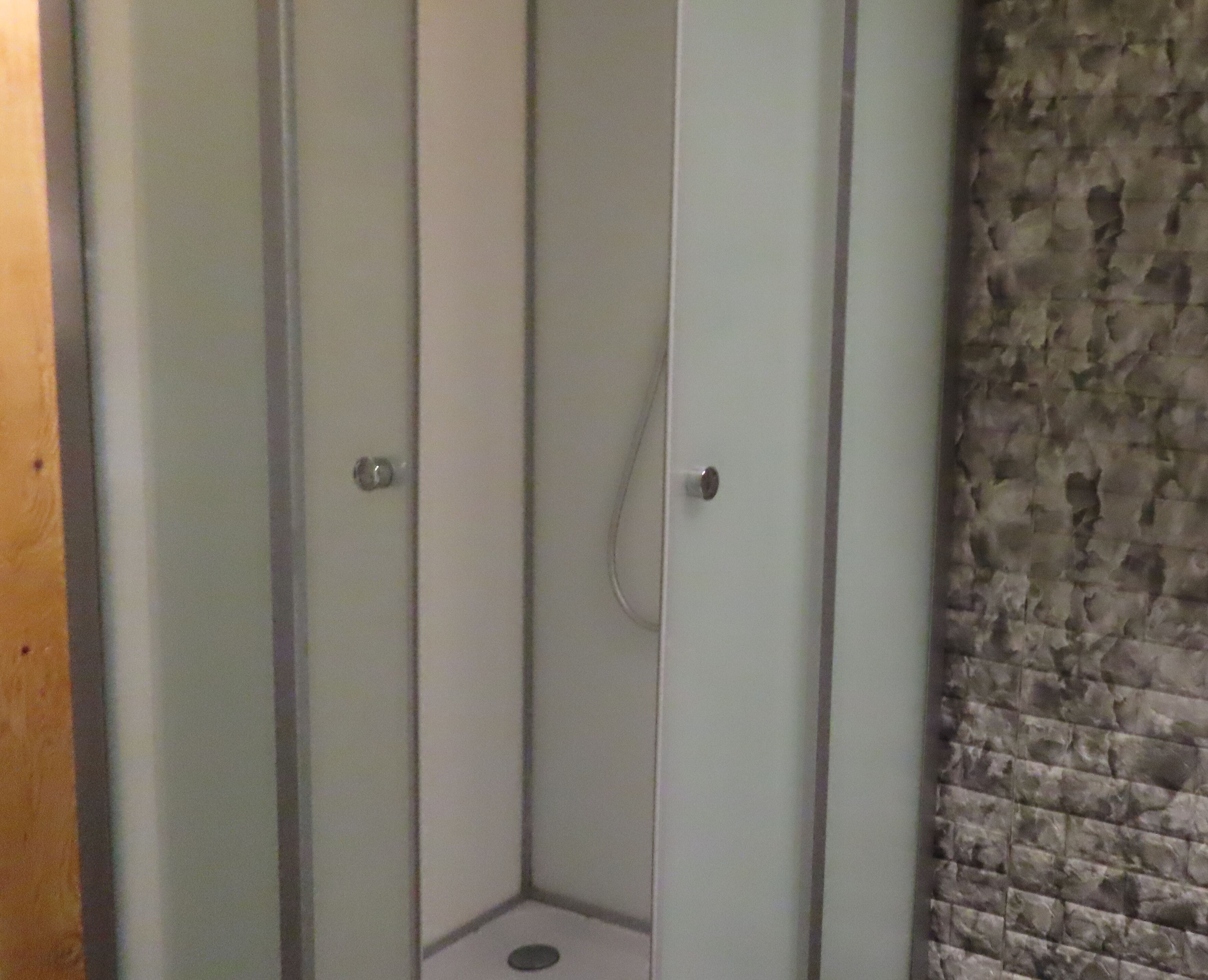Una esquina de habitación con una puerta blanca y una pared de piedra.