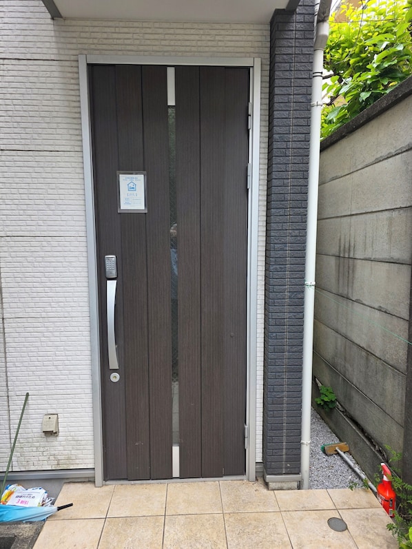 A closed sliding door with a keypad lock, a small sign above it, and a tiled entrance area.