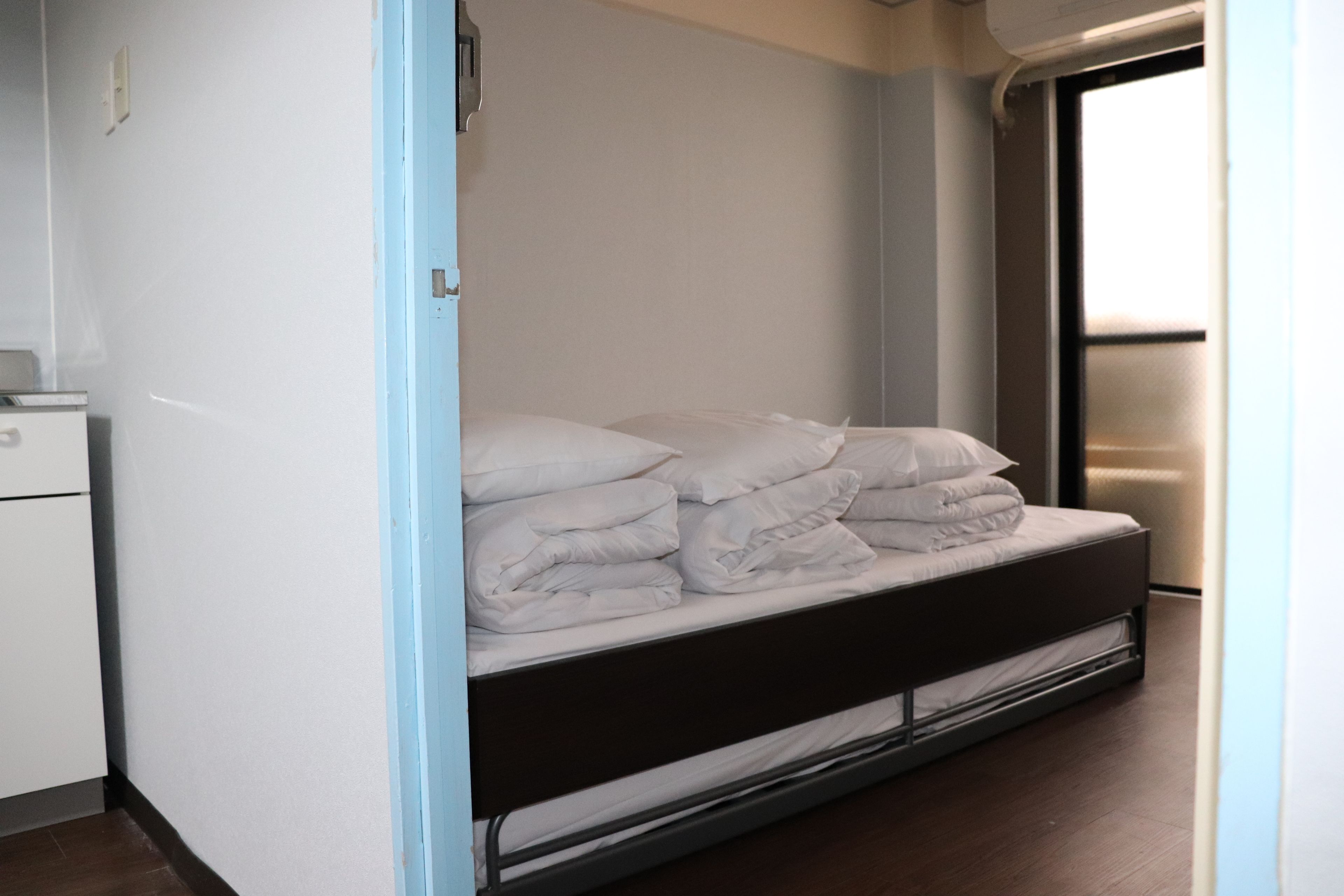 A compact room with a bed, a small desk, and a window.