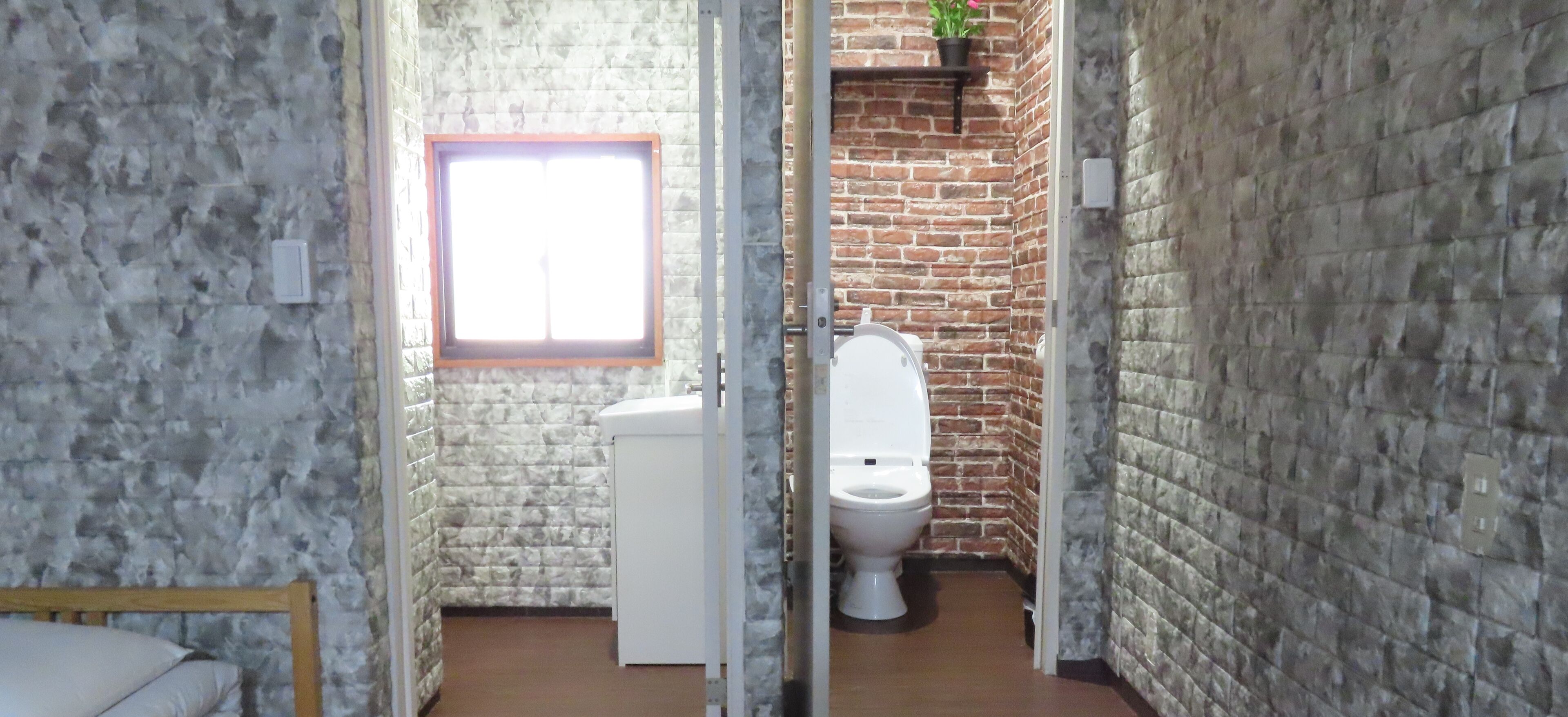 A bathroom with a white toilet, a window, and a brick wall.