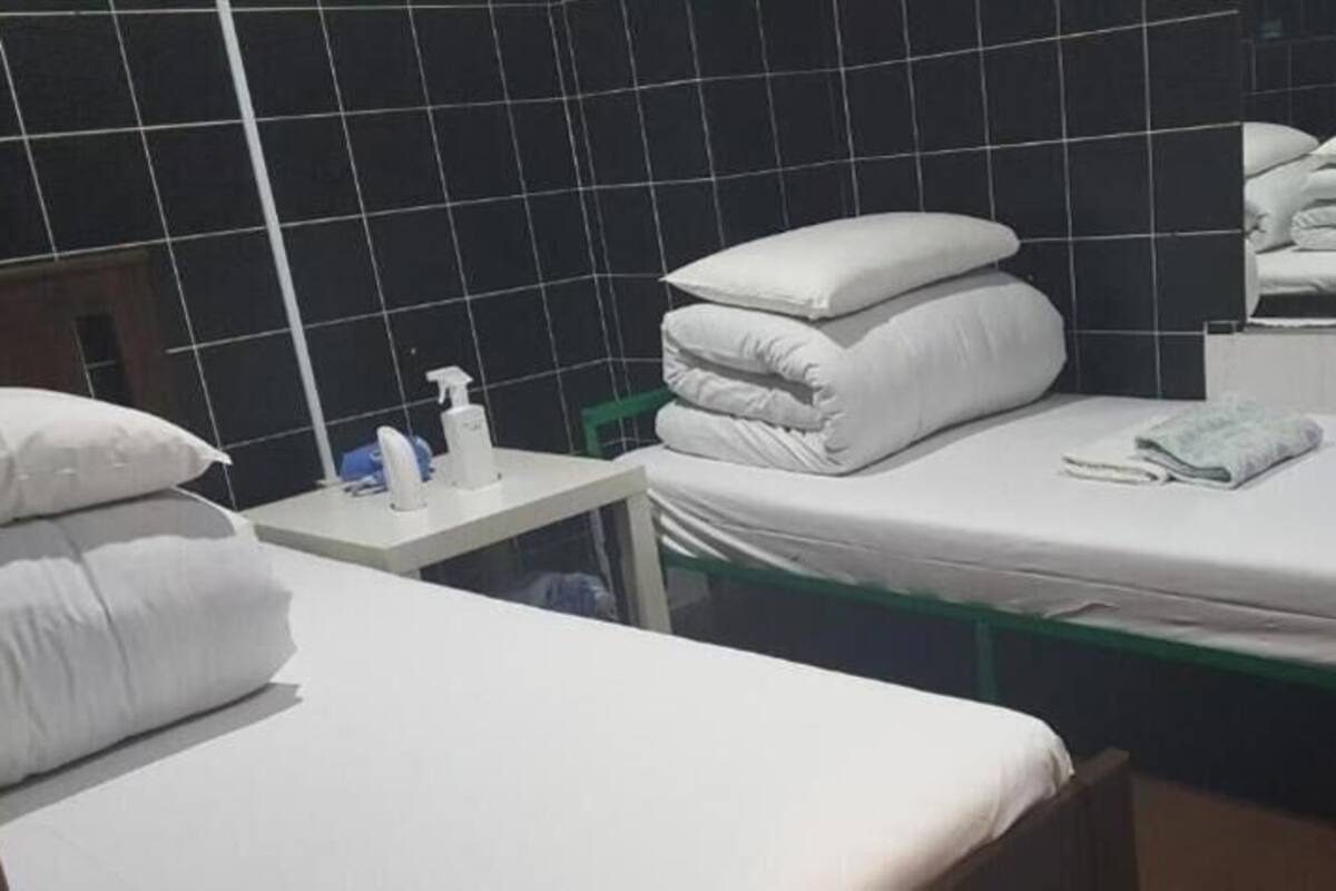 Hotellihuone, jossa on kaksi sänkyä, pieni pöytä, jossa on hygieniatarvikkeita, ja peili.