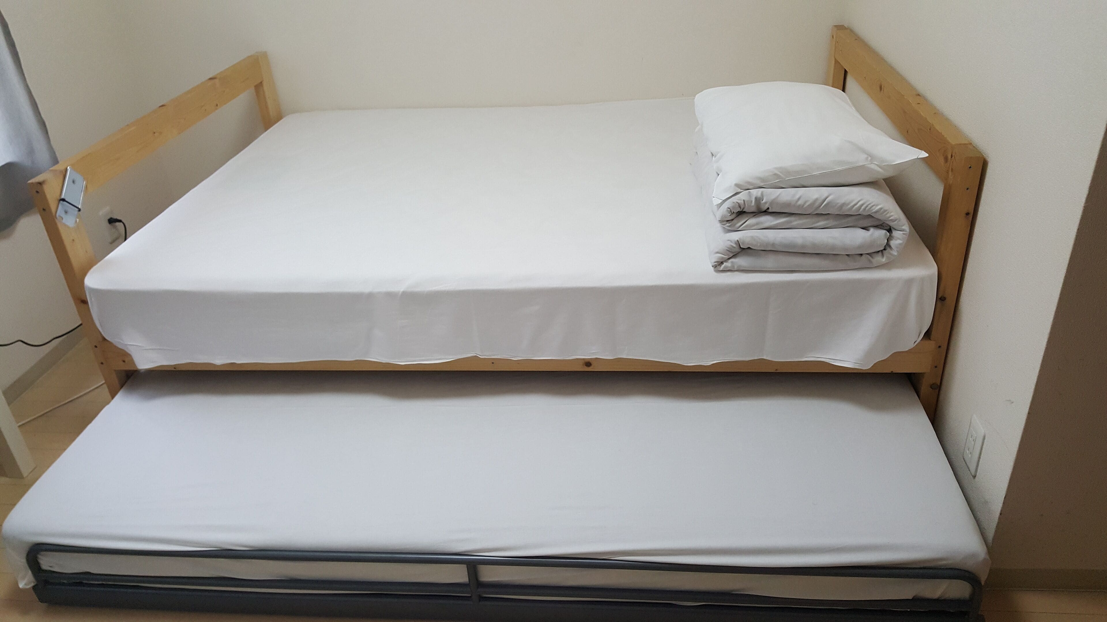 A bunk bed with two levels, each with a white mattress and a wooden frame.