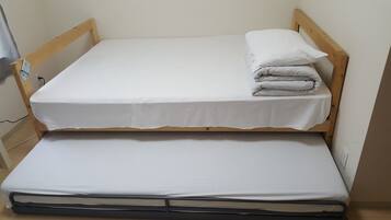 A bunk bed with two levels, each with a white mattress and a wooden frame.