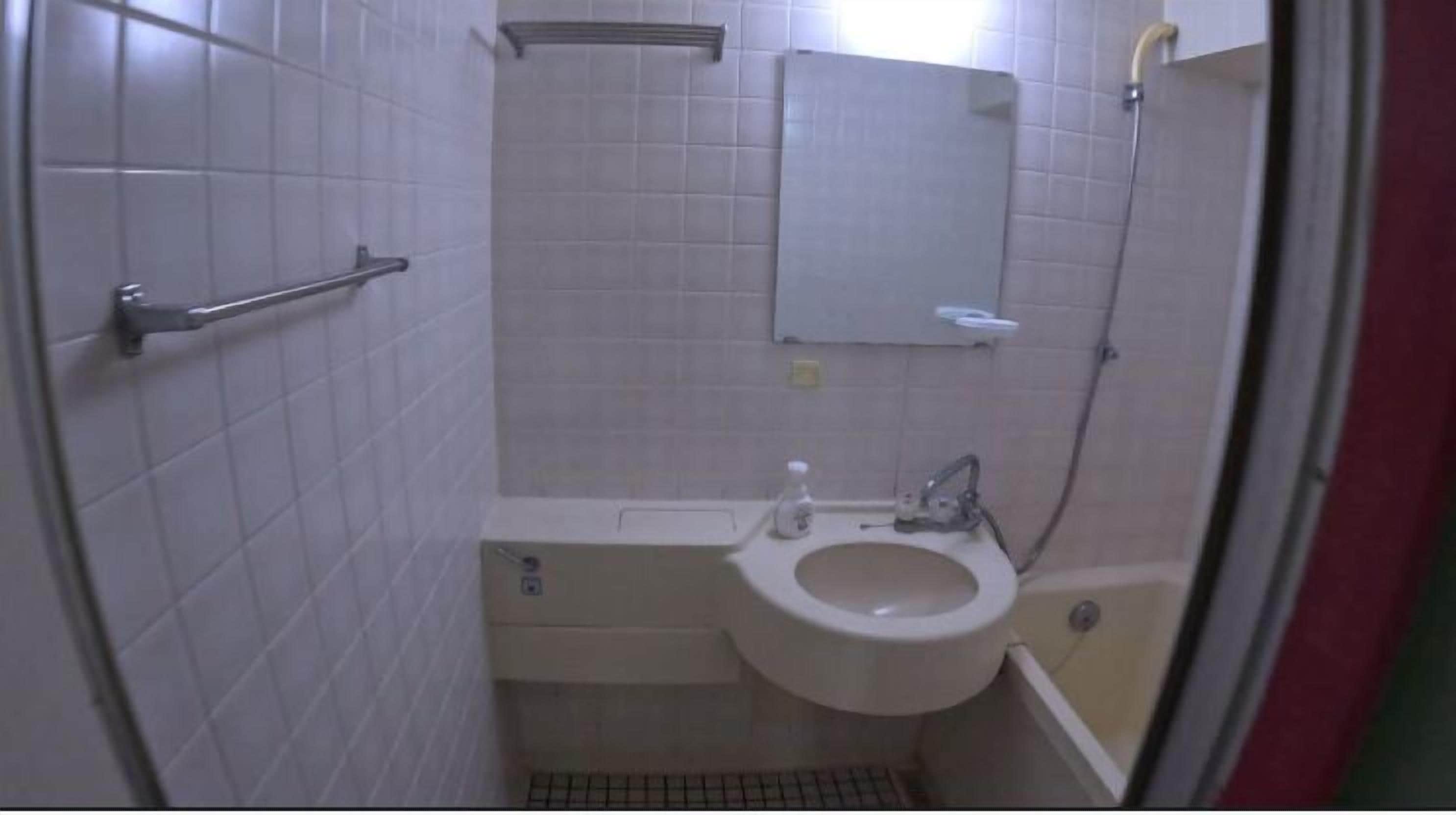 Un baño pequeño y funcional con inodoro, lavamanos y ducha.