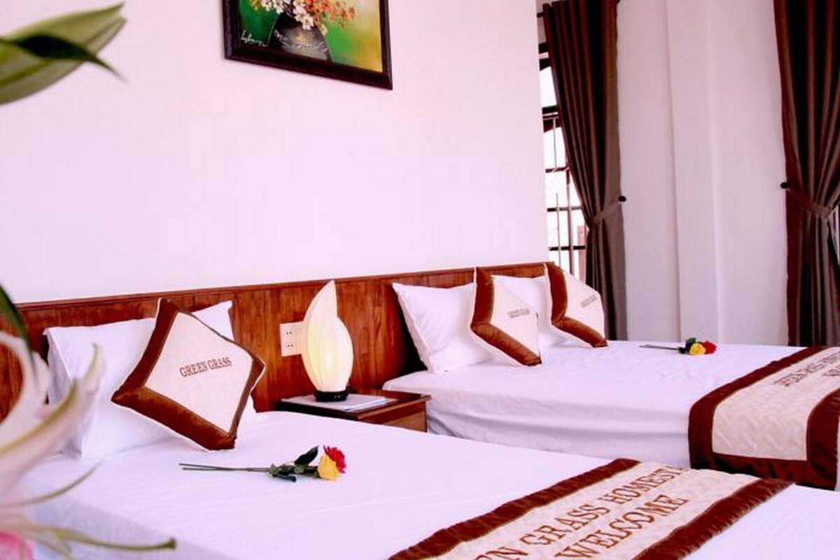 A hotel room with two beds, a nightstand, a lamp, and a painting on the wall.
